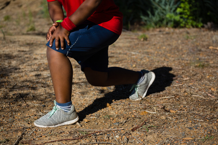 Low-section of boy performing stretching exercise during obstacle course trainingの写真素材