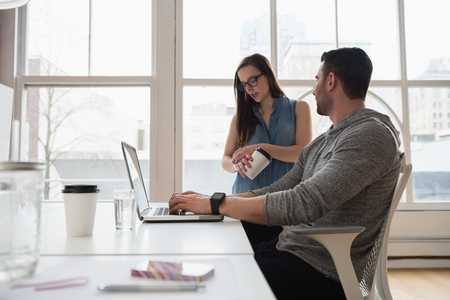 Executives discussing over laptop in officeの写真素材