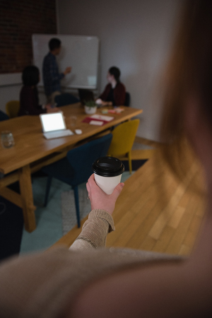 Female executive holding coffee cup in office