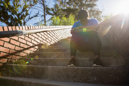 Upset woman sitting on staircase in the boot camp on a sunny dayの写真素材