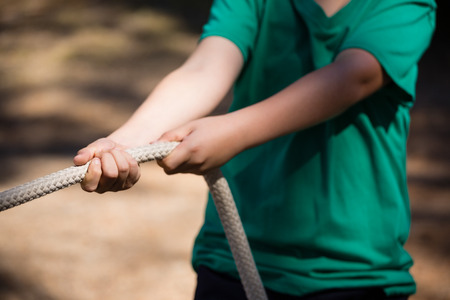 Mid-section of boy practicing tug of war during obstacle course training in the boot campの写真素材