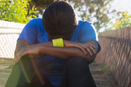 Upset woman sitting on staircase in the boot camp on a sunny dayの写真素材