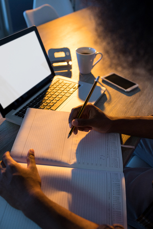 Male executive writing in diary at his desk in officeの写真素材