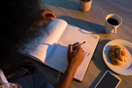 Male executive writing in diary at his desk in officeの写真素材