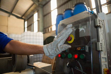 Hand pressing a control button in factory