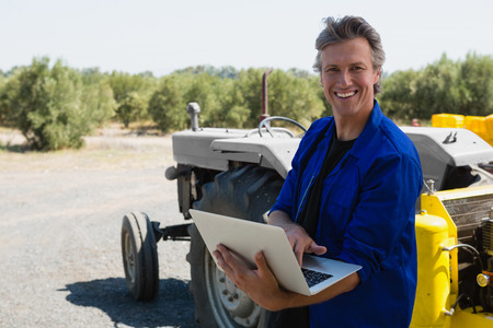 Portrait of smiling worker using laptop on road
