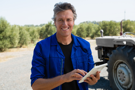 Portrait of smiling worker using tablet on road on a sunny dayの写真素材