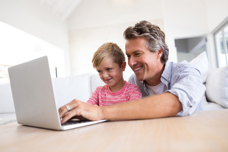 Father and son using laptop in living room at homeの写真素材