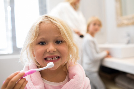 Portrait of girl brushing teeth in bathroomの写真素材