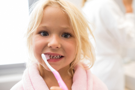 Portrait of girl brushing teeth in bathroomの写真素材