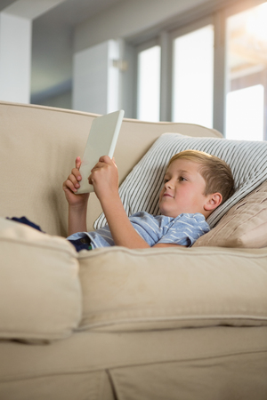 Boy using digital tablet in the living room at homeの写真素材