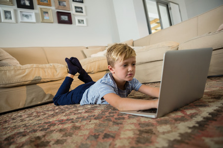 Boy using laptop in the living room at homeの写真素材
