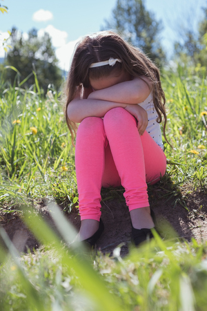 Sad girl sitting in parkland on a sunny dayの写真素材