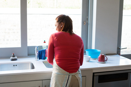 Rear view of woman washing utensil in kitchen sinkの写真素材