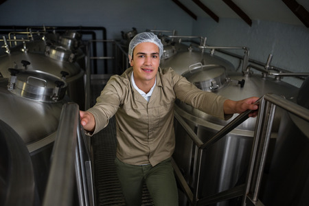 Portrait of male worker standing amidst storage tanks on steps at warehouseの写真素材