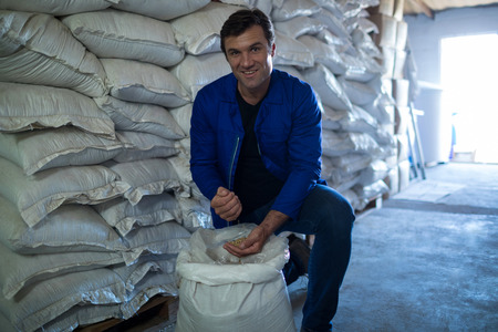 Portrait of smiling worker examining barley at warehouse