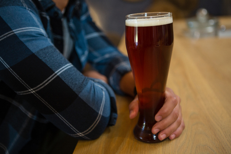 Midsection of man with beer glass at bar counterの写真素材