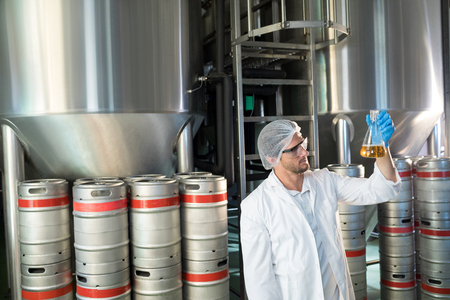 Scientist examining beer in beaker at warehouse