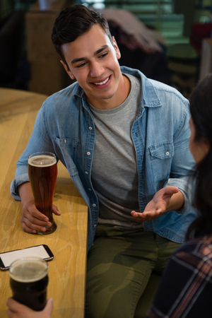Smiling young man interacting with female friend at restaurantの写真素材