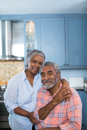 Portrait of smiling couple with arm around in kitchen at homeの写真素材