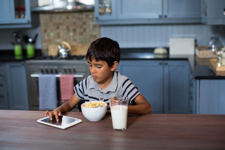 Boy using digital tablet while having cereal breakfast at homeの写真素材