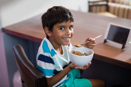 Portrait of boy having breakfast while sitting on chair at home