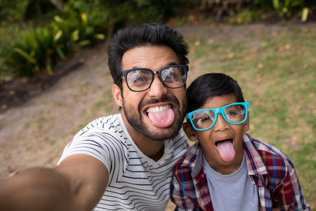 High angle view of father and son wearing sunglasses while sticking out tongueの写真素材