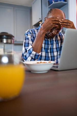 Worried man using laptop while sitting at homeの写真素材