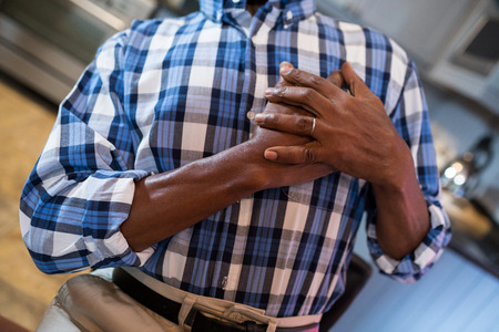 Midsection of man with hand on chest suffering from chest pain while standing at home