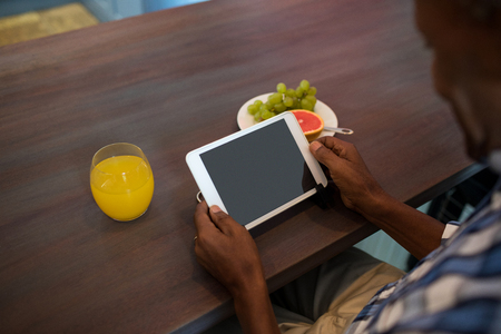 Cropped image of man using tablet while sitting at tableの写真素材