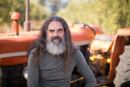 Portrait of happy man sitting against tractor in olive farm on a sunny dayの写真素材