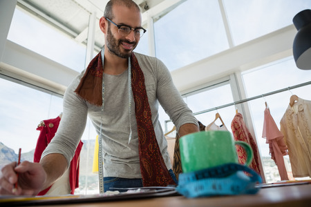Low angle view of smiling designer working at table in studio