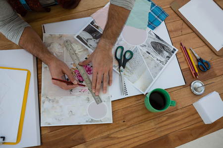 Cropped hands of designer drawing line on paper at table in officeの写真素材