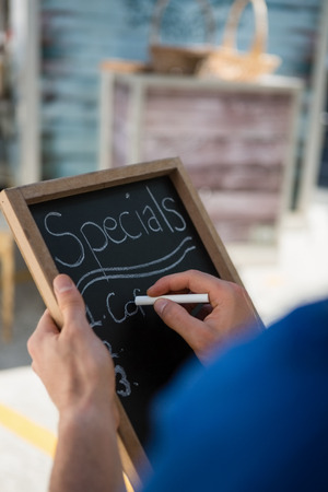 Cropped hand of owner writing menu at food truckの写真素材