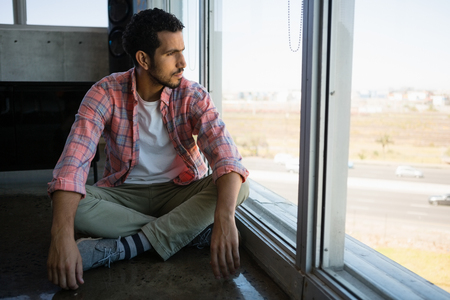 Full length of young businessman looking through window at officeの写真素材