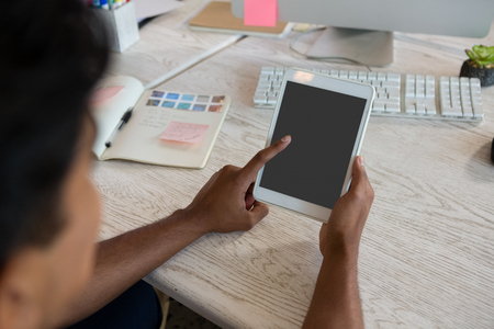 Cropped image of man using digital tablet at desk in creative officeの写真素材