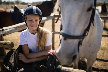 Portrait of smiling girl leaning on the fence in ranchの写真素材
