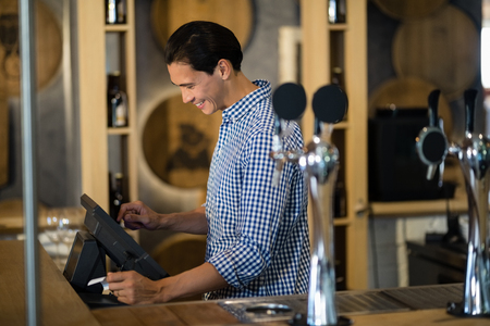 Bar tender operating cash desk at counter in restaurantの写真素材