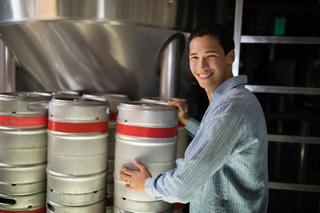 Portrait of manager checking beer keg in warehouse of restaurant