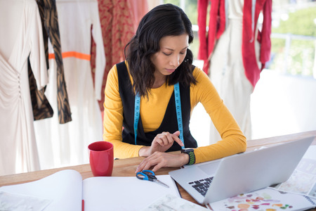 Female designer adjusting smart watch in office