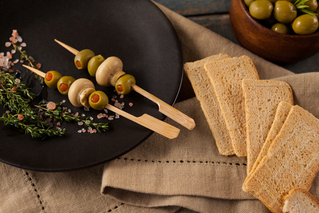 Crackers by green olives served in plate on napkin at tableの写真素材