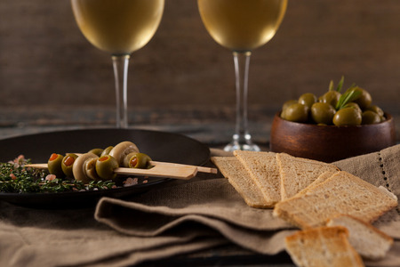 Close up of crackers with olives served in plate by white wine on tableの写真素材