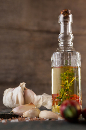 Close up of herb with oil in container by garlic on table against wallの写真素材