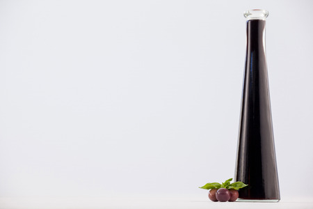 Close up of red olives with oil bottle against white backgroundの写真素材