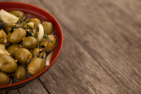 Cropped image of olives with garlic and oil in bowl on wooden tableの写真素材