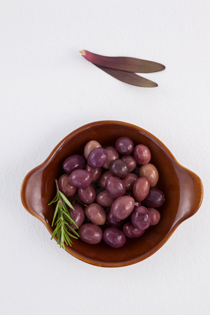 Overhead view of olives and rosemary in wooden container on tableの写真素材