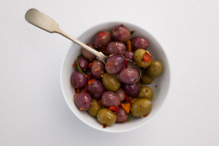Overhead view of olives and spices with spoon in bowl on tableの写真素材