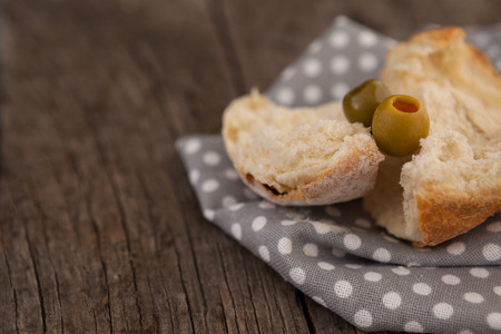 Close up of bread and green olives on napkin at wooden tableの写真素材