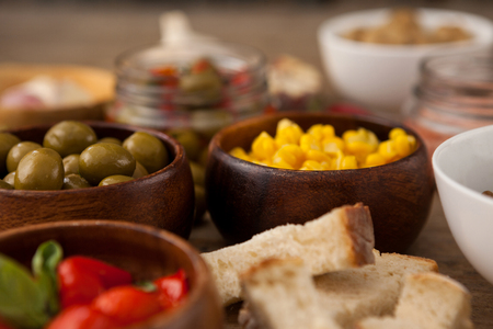 Olives and corns in bowls by ingredients on tableの写真素材