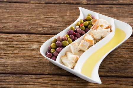 Close-up of marinated olives, bread pieces and olive oil in platterの写真素材